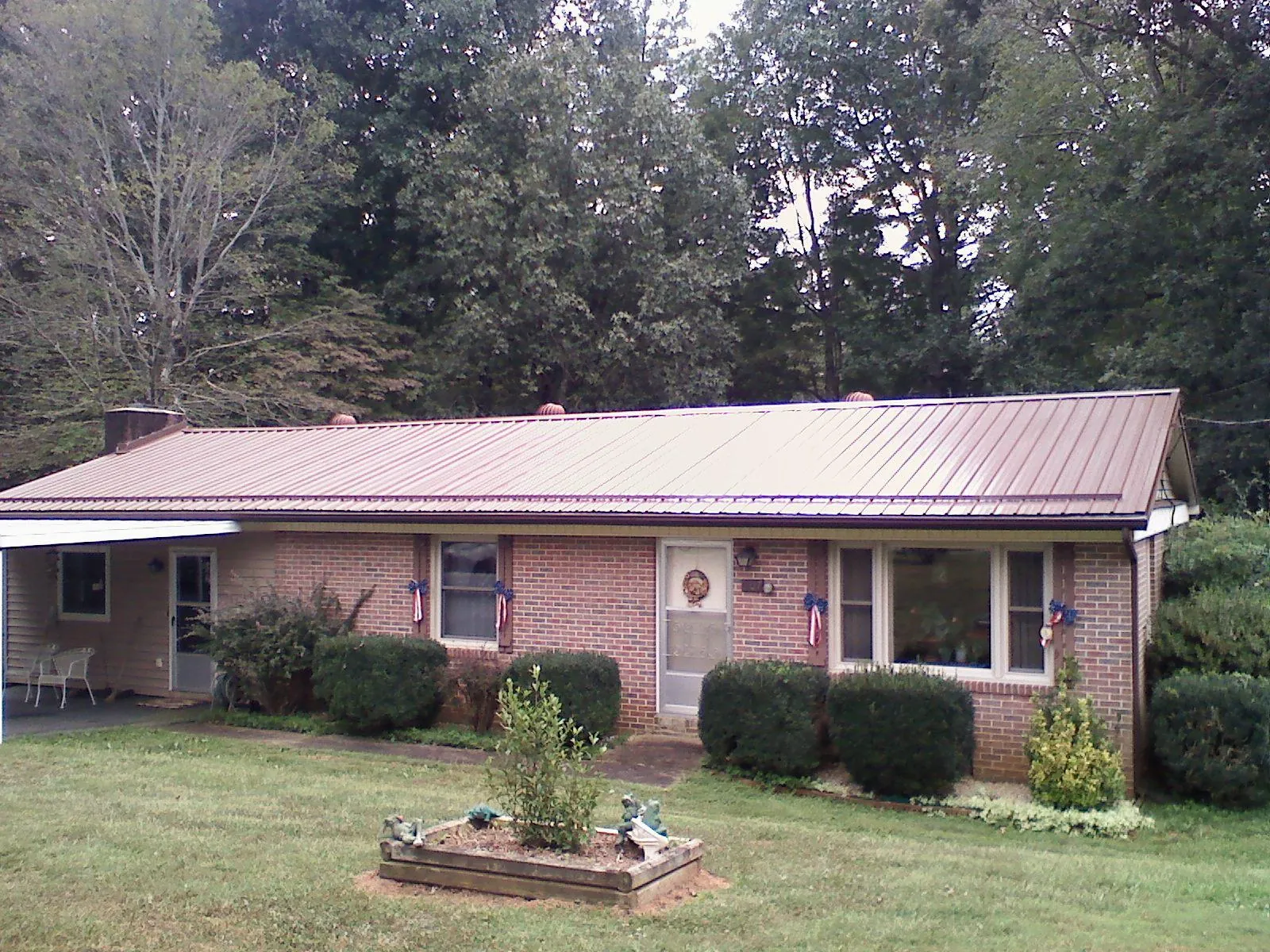 Bronze metal roof on a brick ranch home with a carport in Holloway