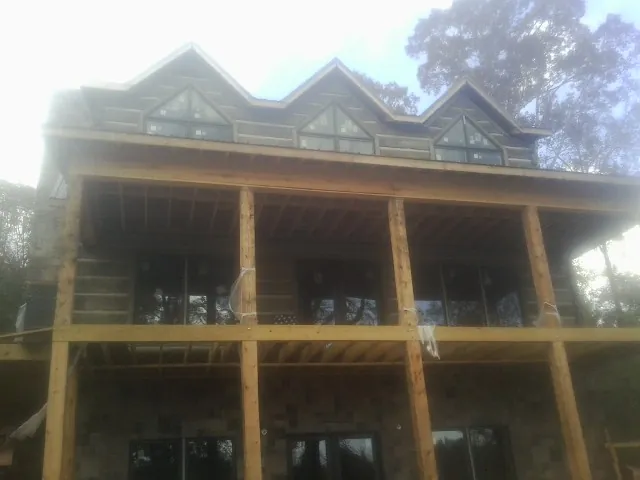 Dormers and porch framing on a large log home under construction — Roof Coating work by our crew in Holloway