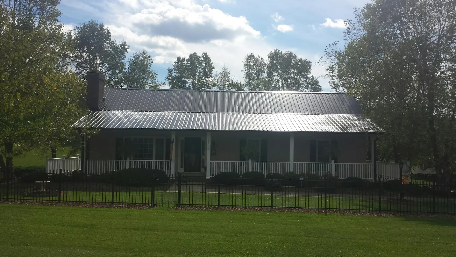 Gray metal roof on a brick ranch with a full width front porch — Gutter Guard Installation work by our crew in Holloway