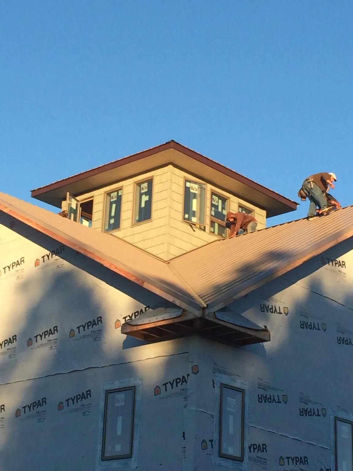 Roofers working around a rooftop cupola on a new metal roof at sunset — Roof Waterproofing in Holloway by Roofing Brothers